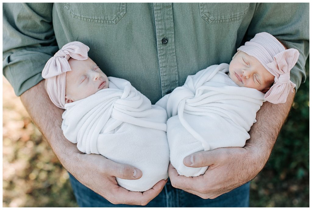 dad holding twin girl newborns 