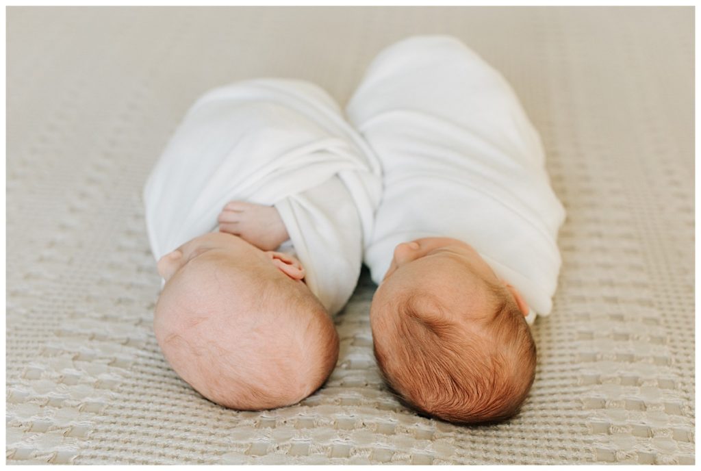 twin newborn sisters laying on a bed 