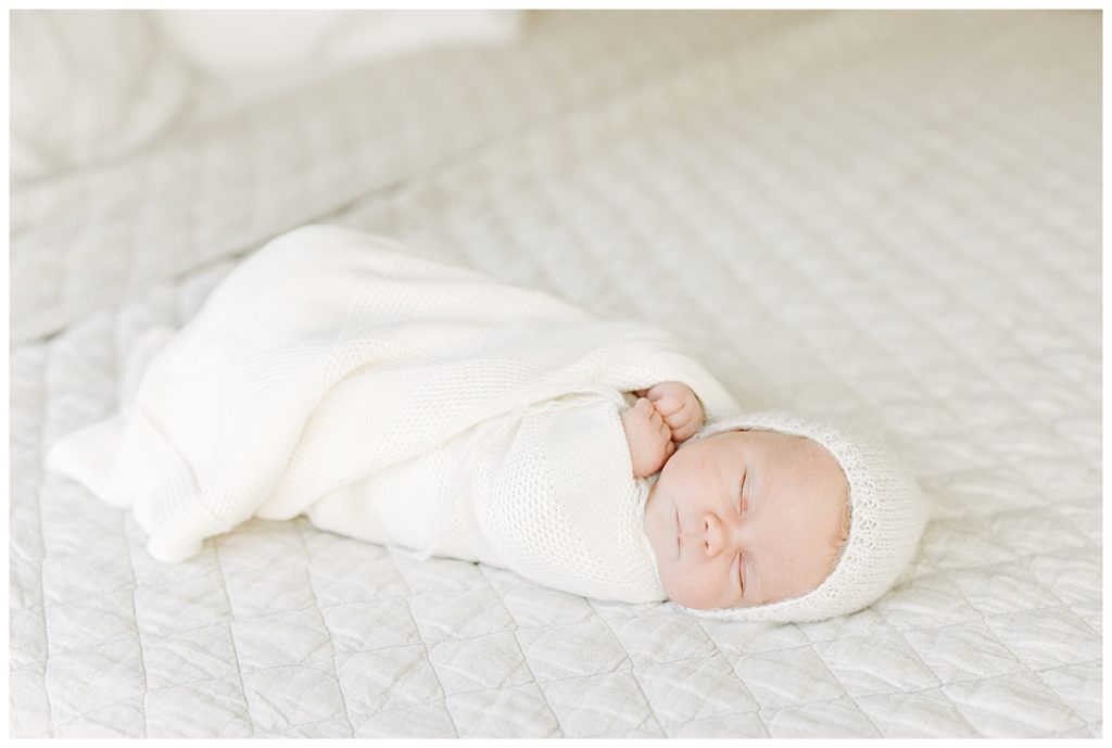 baby girl in cream blanket and bonnet 