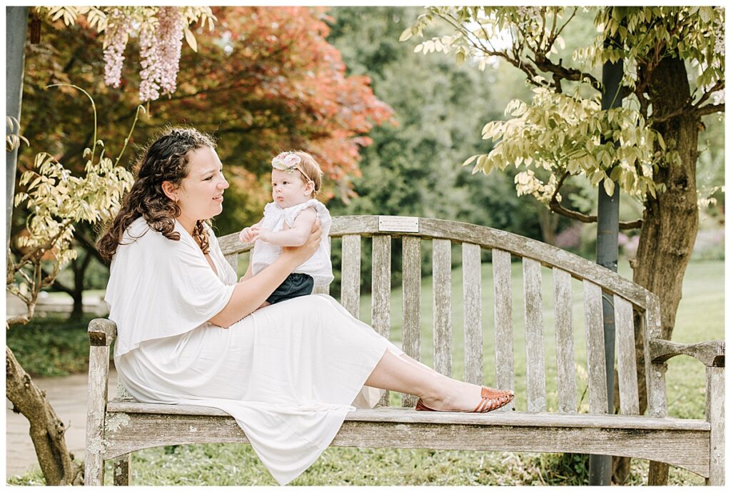 mother holding baby girl on a garden bench 