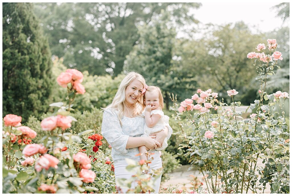 mother holding daughter in rose garden 