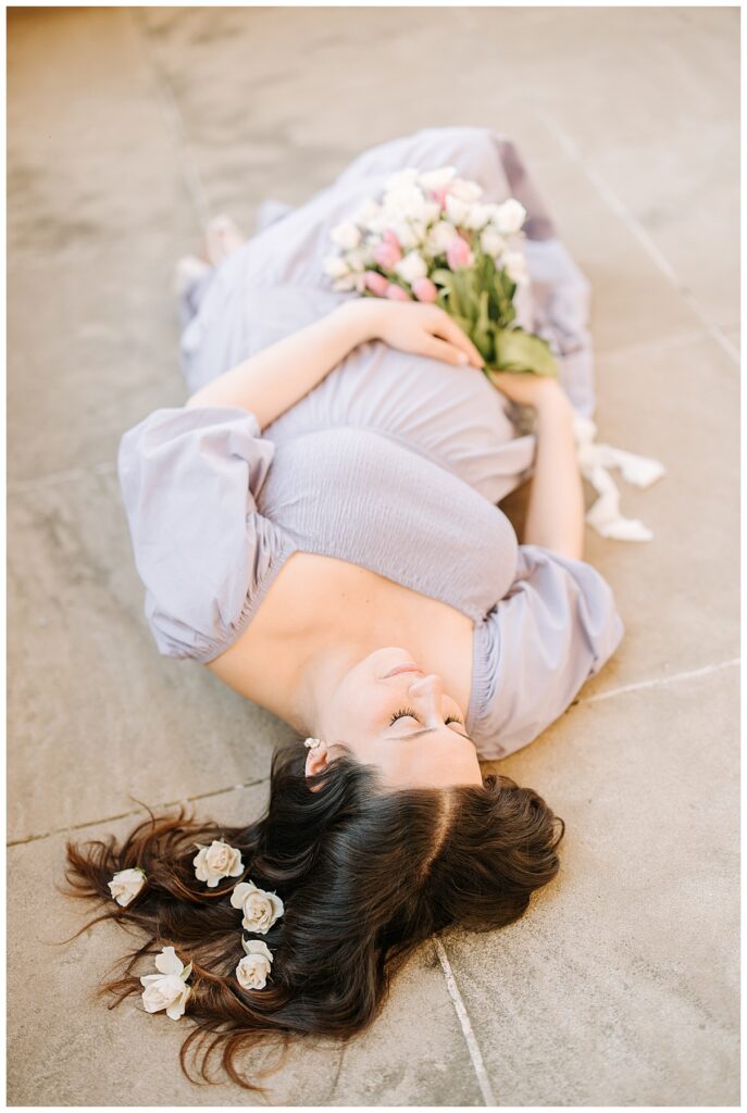 expectant mother laying down with flowers in her hair 