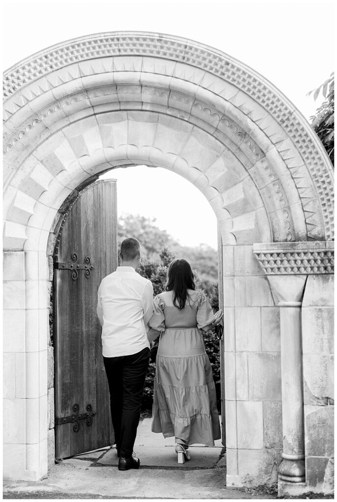 couple walking through a stone archway 