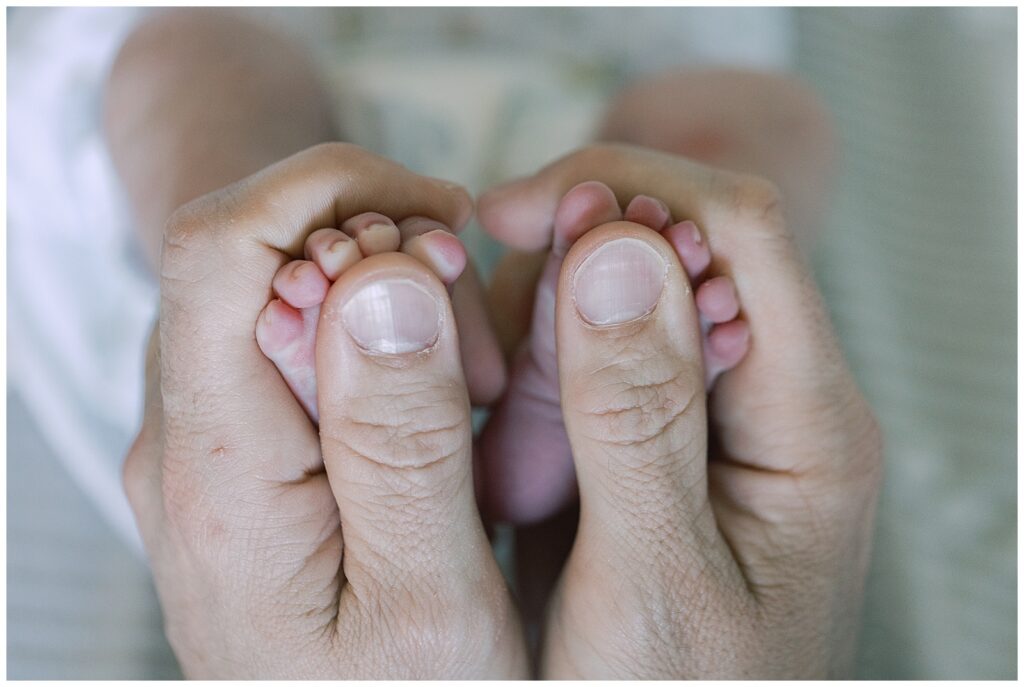 fathers hands around newborn toes 